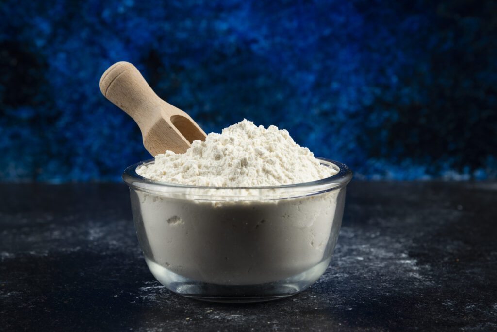 Glass bowl of creatine on blue background. High quality photo