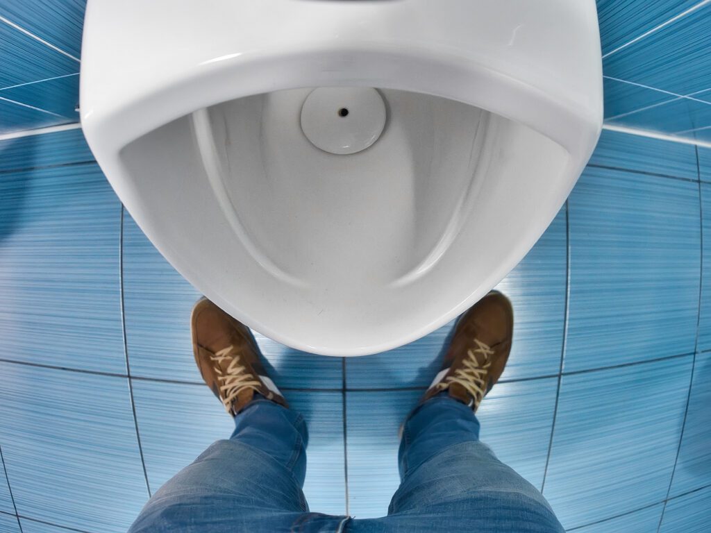Man stands in front of toilet in toilet and tries to urinate. First-person view. Urinary problem and male disease prostatitis..