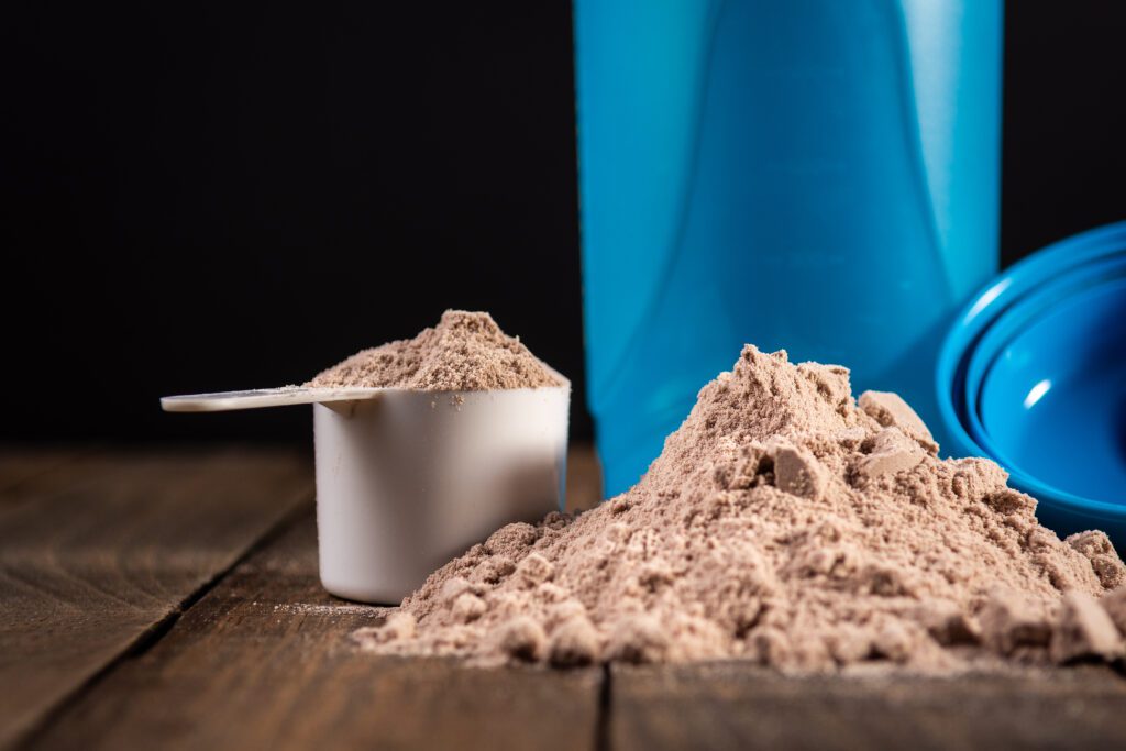 Measuring scoop of whey protein on wooden table to prepare a milkshake. Concept of diet, health and exercise