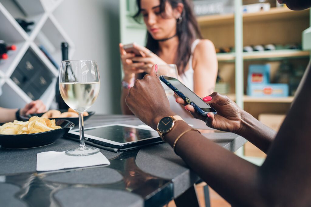 Multiethnic girls drinking and chatting with smartphone – connection; youth; technology